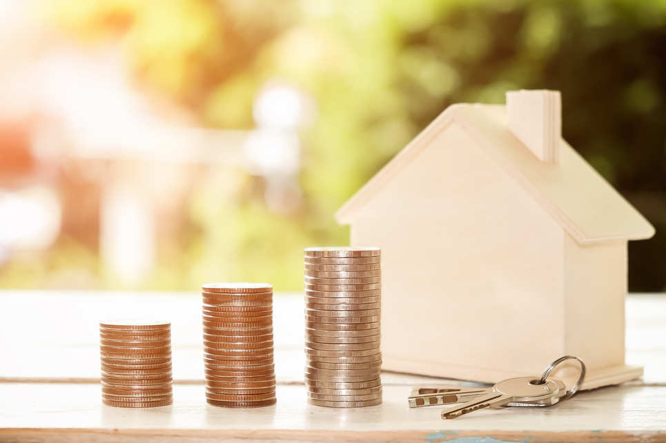 Hand Putting Coin in House Model of Coin for Saving Money for Buying House